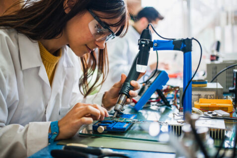 A woman works on a circuit board. CircuiTek offers advice on When Not to Use Heavy Copper PCBs