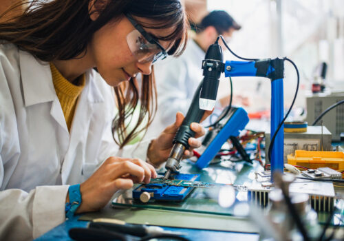 A woman works on a circuit board. CircuiTek offers advice on When Not to Use Heavy Copper PCBs
