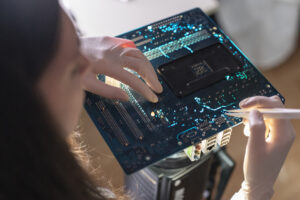 A person holds a circuit board with white gloves and checks the connections to troubleshoot signal loss issues
