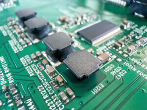 A detailed macro shot of a printed circuit board featuring inductors, capacitors, resistors, and an integrated circuit chip mounted on a vibrant substrate, illustrating How Advanced PCB Design Can Reduce the Need for Additional Heat Sinks